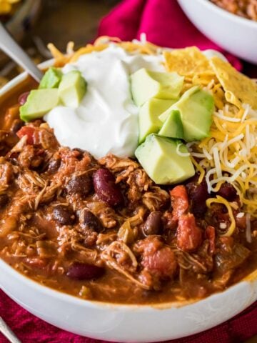 Bowl of turkey chili topped with sour cream, avocado, and shredded cheese.