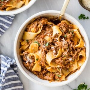 Overhead view of a bowl of beef ragu served with wide pasta noodles.