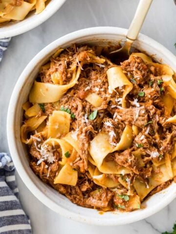 Overhead view of a bowl of beef ragu served with wide pasta noodles.