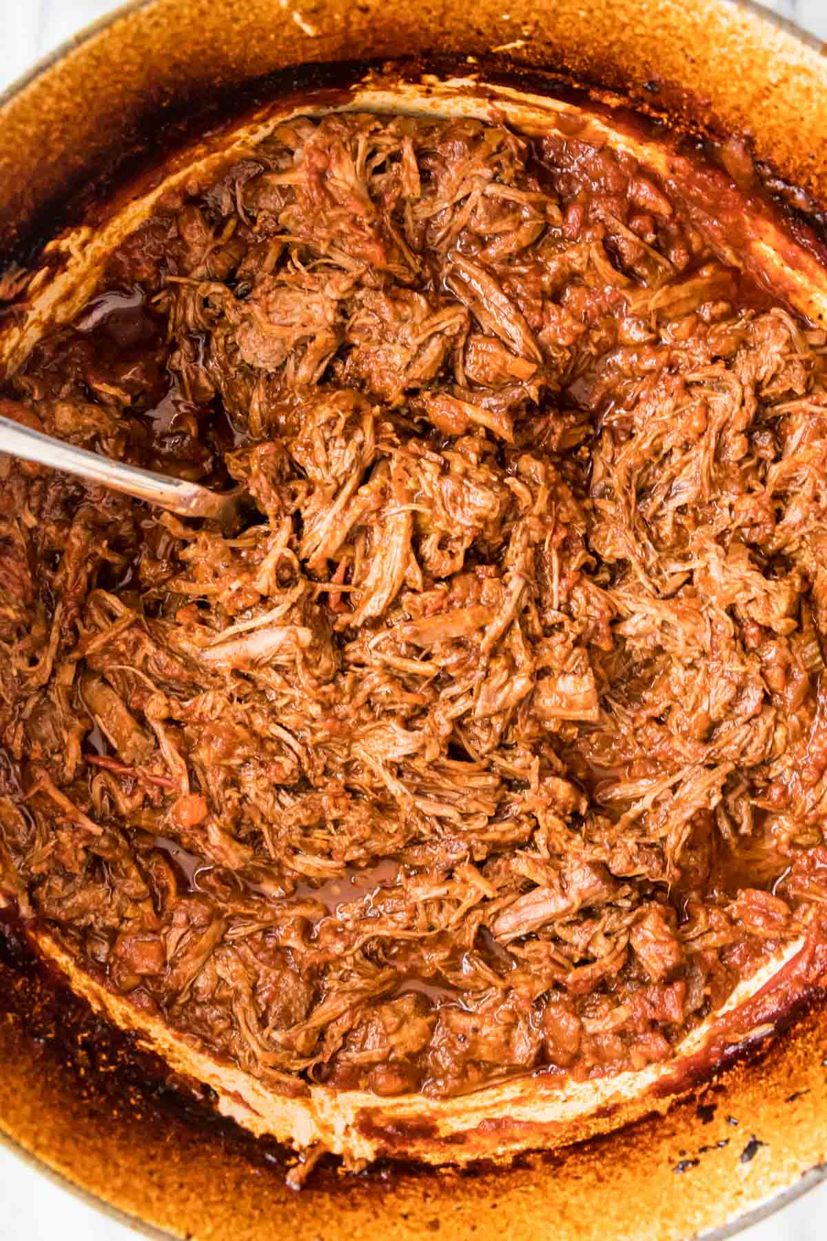 Overhead view of shredded beef in a tomato sauce.
