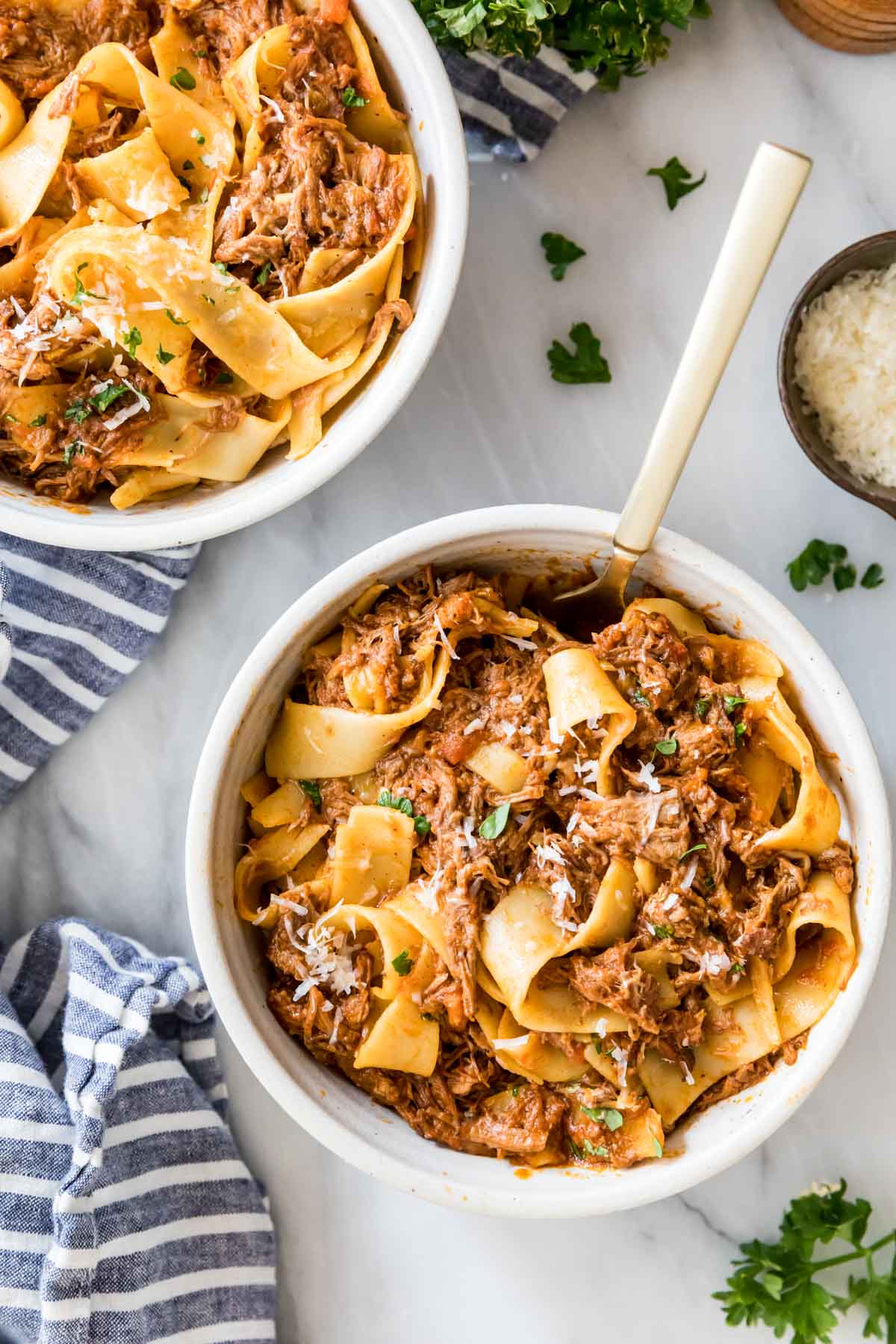 Overhead view of bowls of beef ragu served with wide pasta noodles.