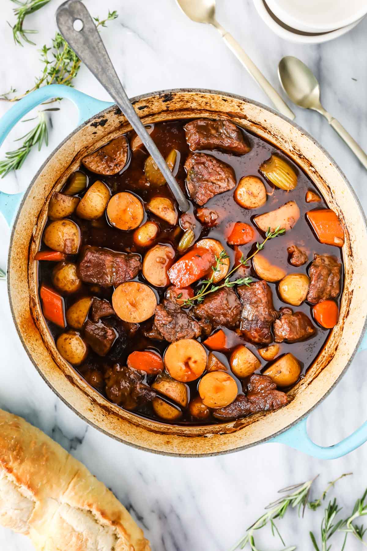 Overhead view of a pot of stew with chunks of beef, carrots, and potatoes.