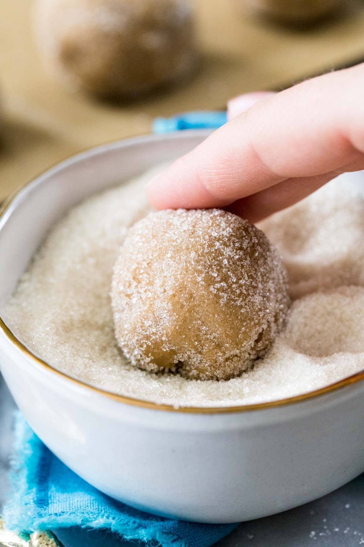 Cookie dough ball being rolled in sugar.