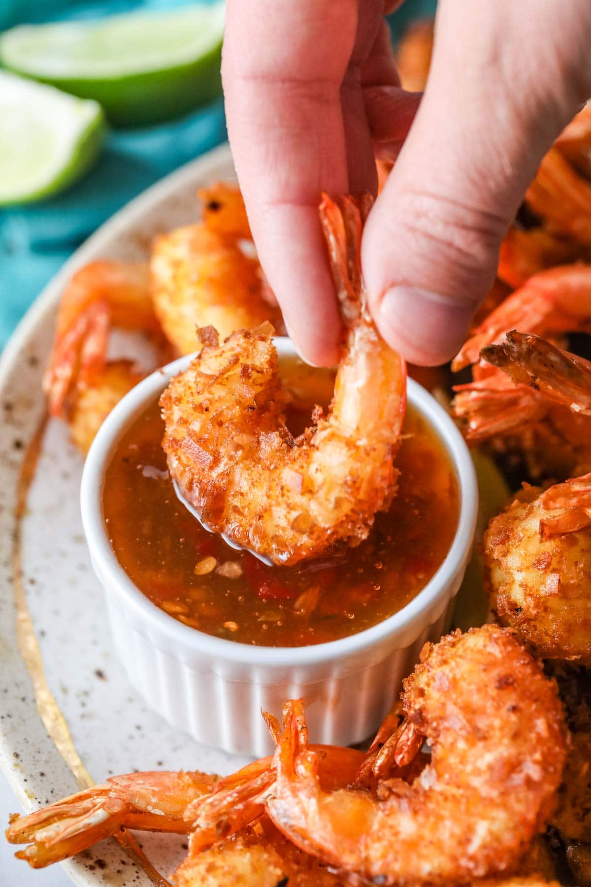 Fried shrimp being dipped into a sweet thai chili dipping sauce.