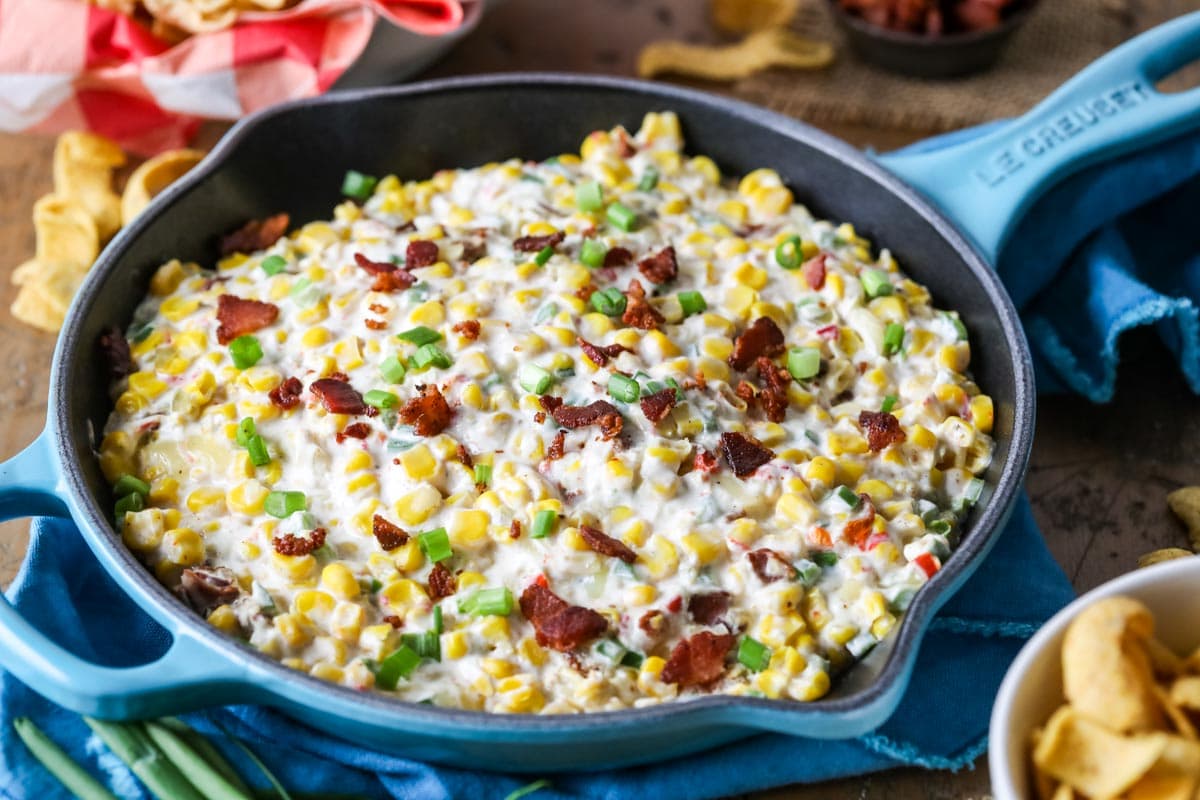 Skillet of dip made with corn, bacon, scallions, and cheese.