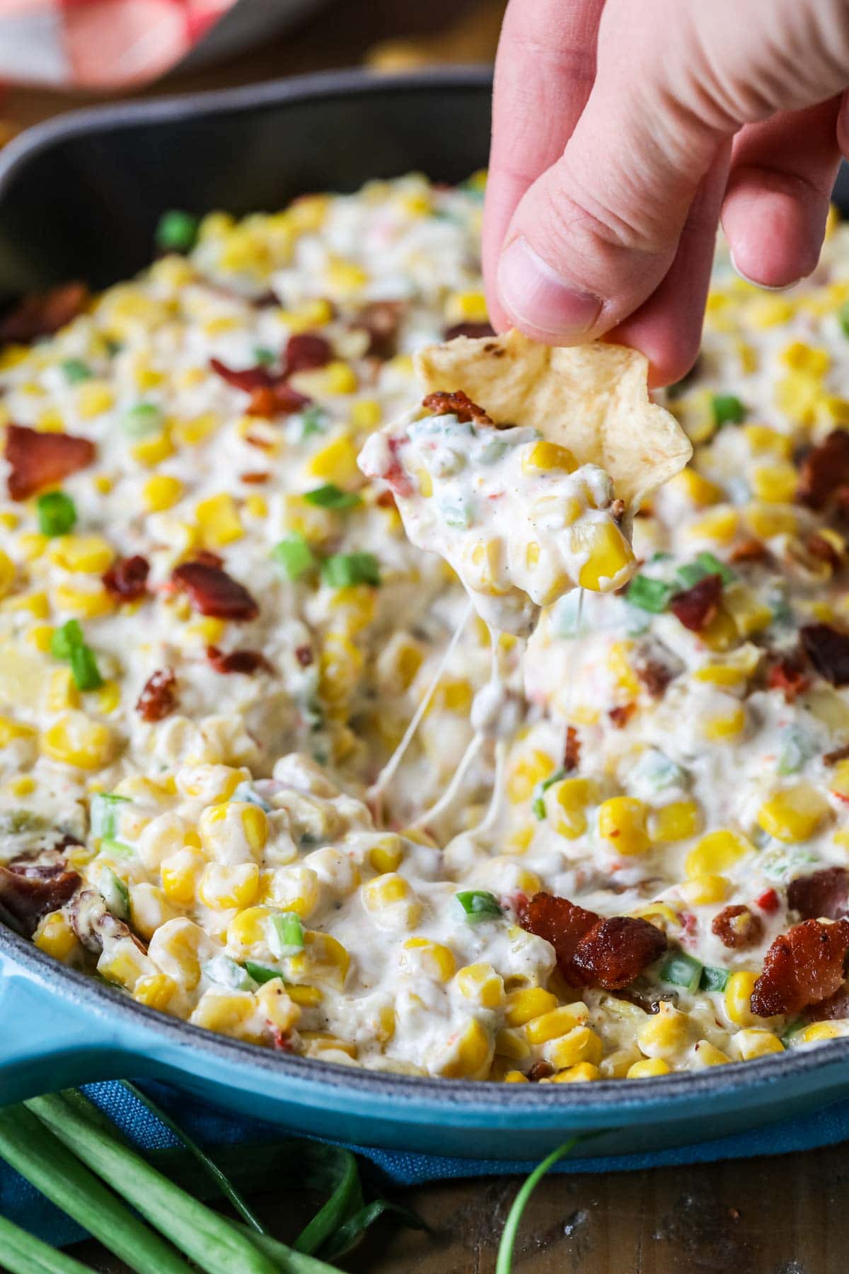 Tortilla chip scooping dip out of a skillet.