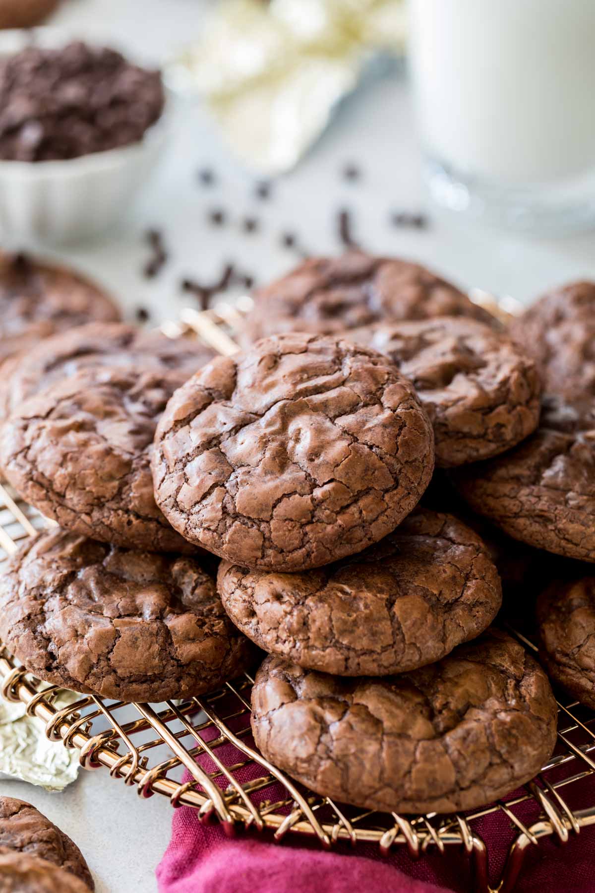 Crinkly-topped flourless chocolate cookies stacked in a pile on a metal cooling rack.