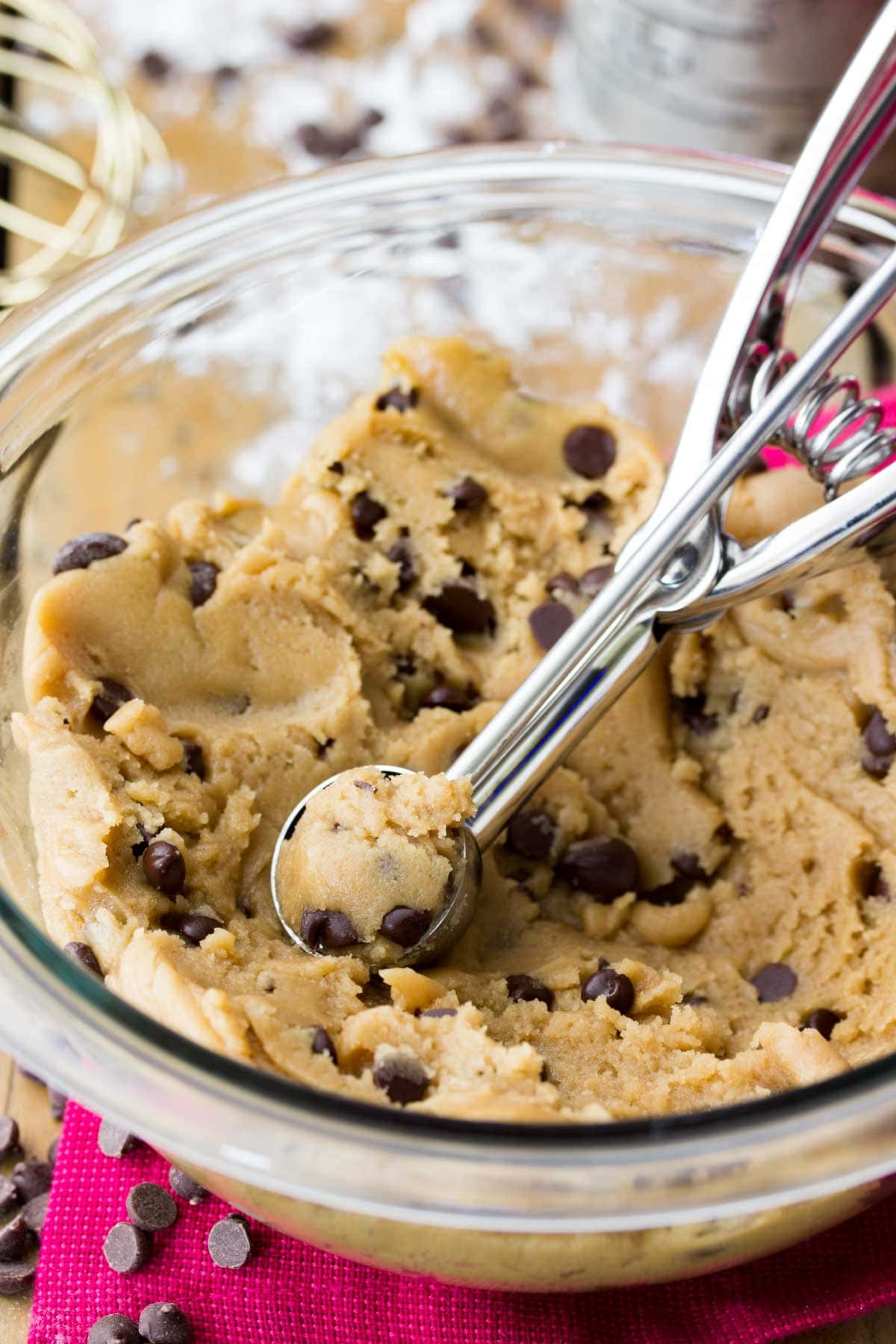 Small cookie scoop in a bowl of chocolate chip cookie dough.