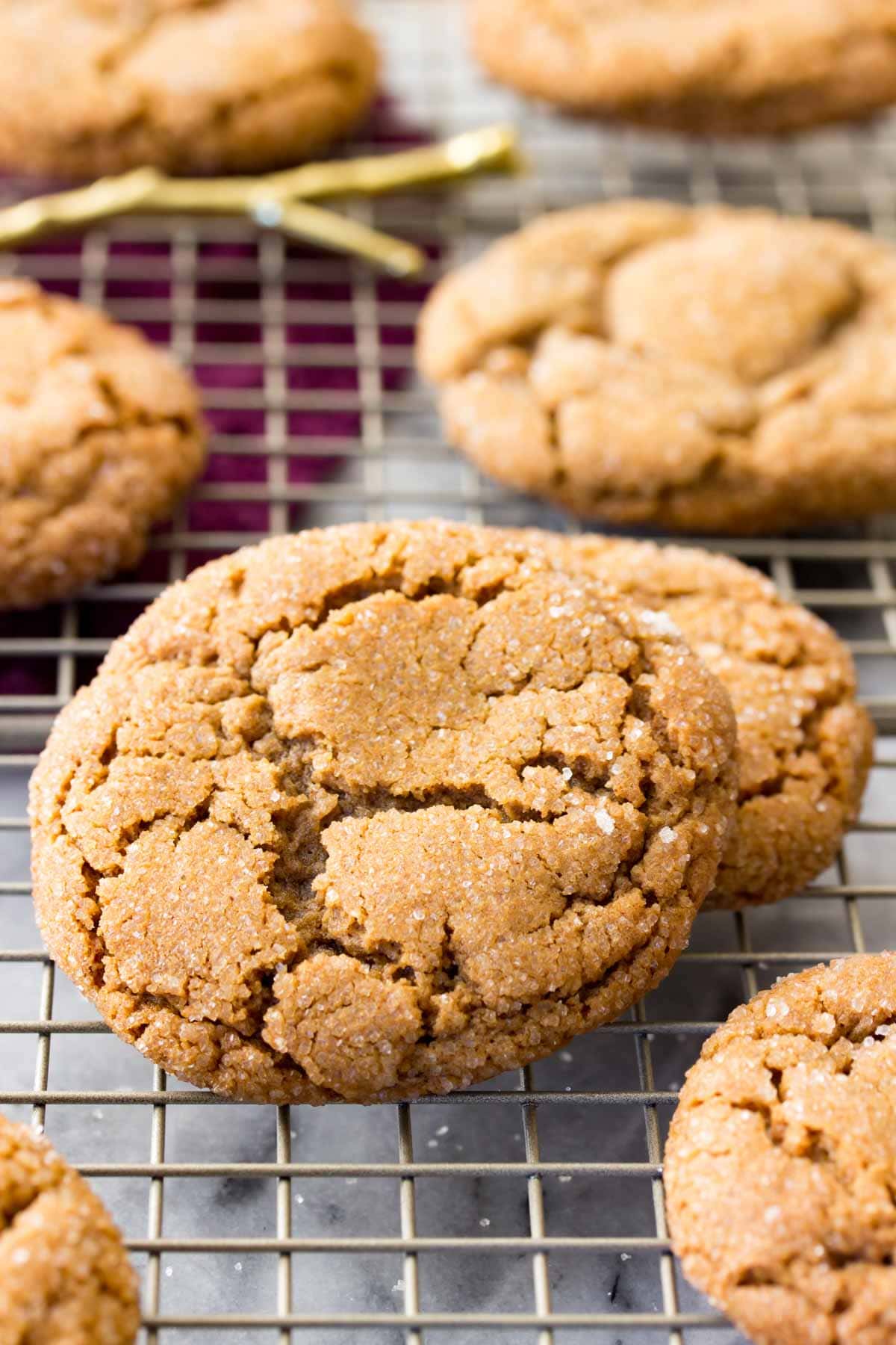 Crackly topped molasses cookies on a cooling rack after baking.