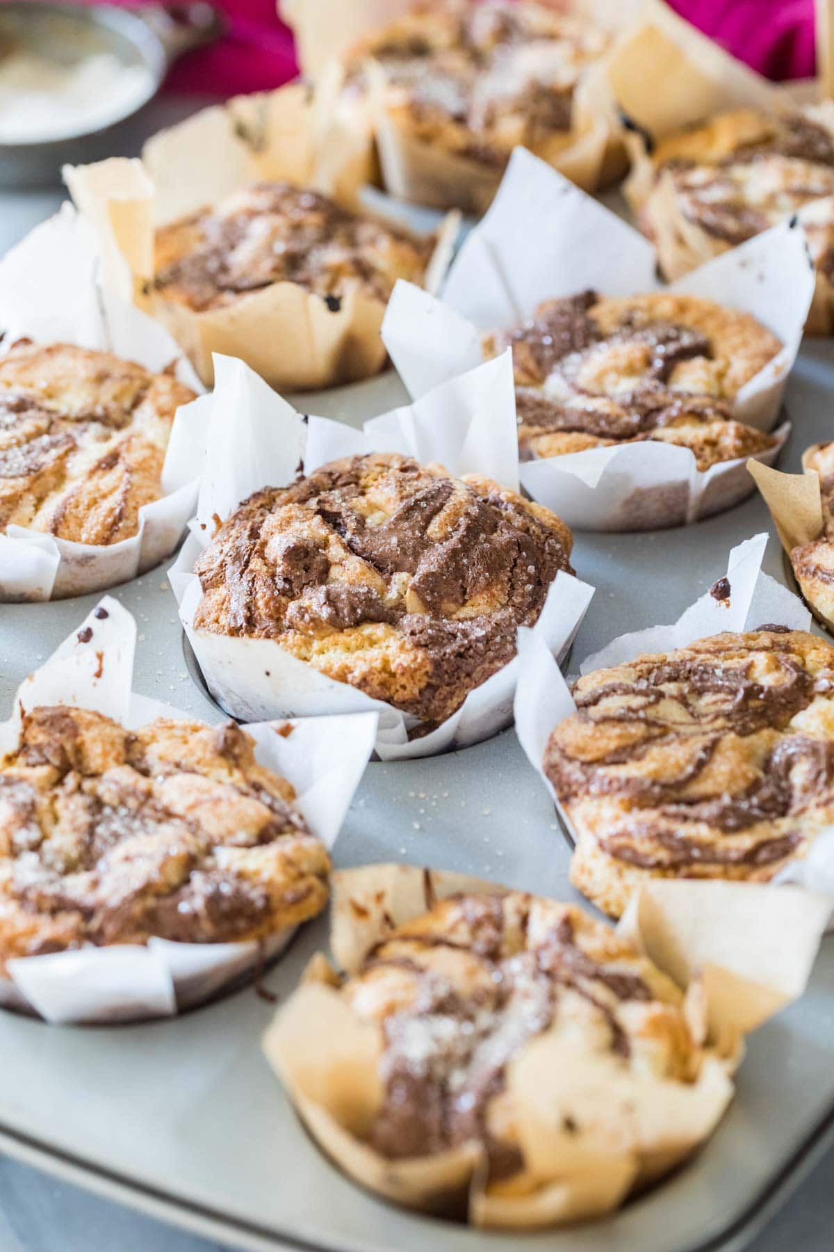 Muffins with swirled chocolate tops in their muffin tin.