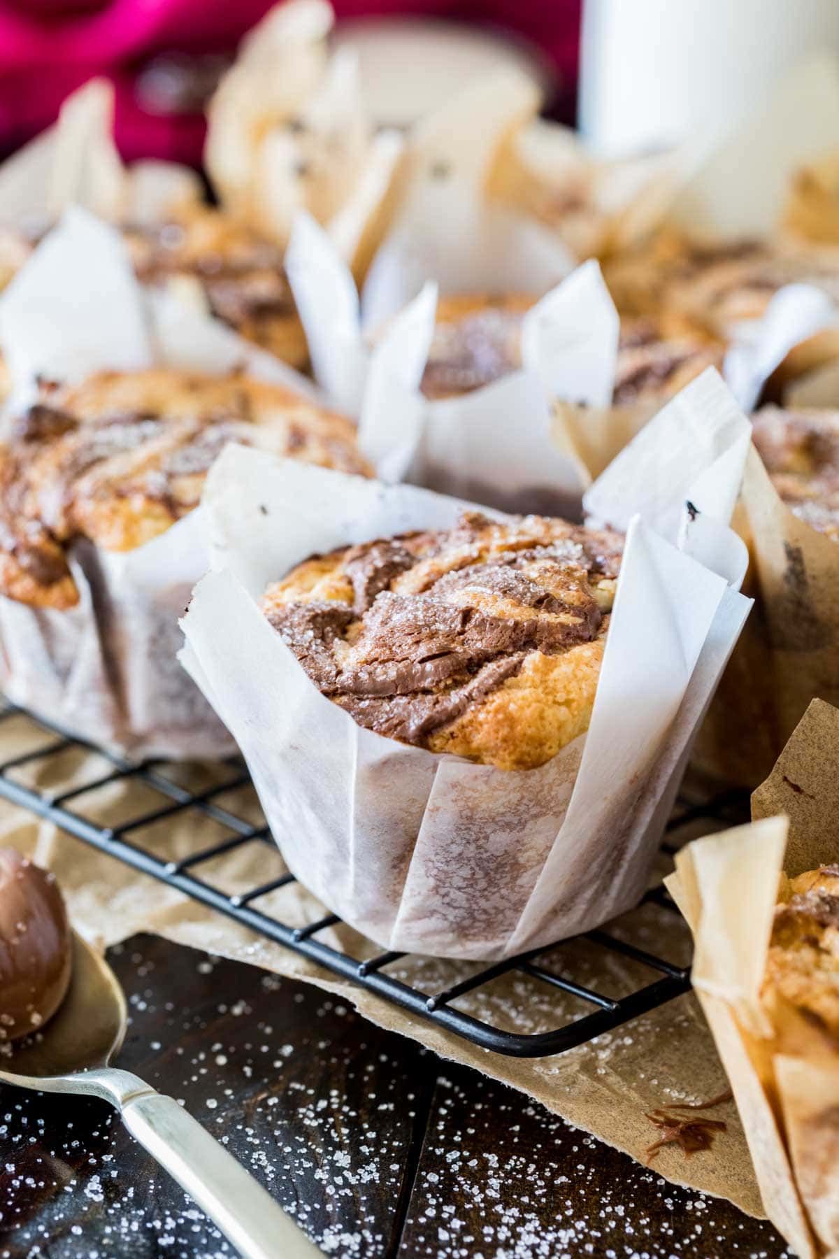 Muffins with swirled chocolate tops in parchment paper liners.