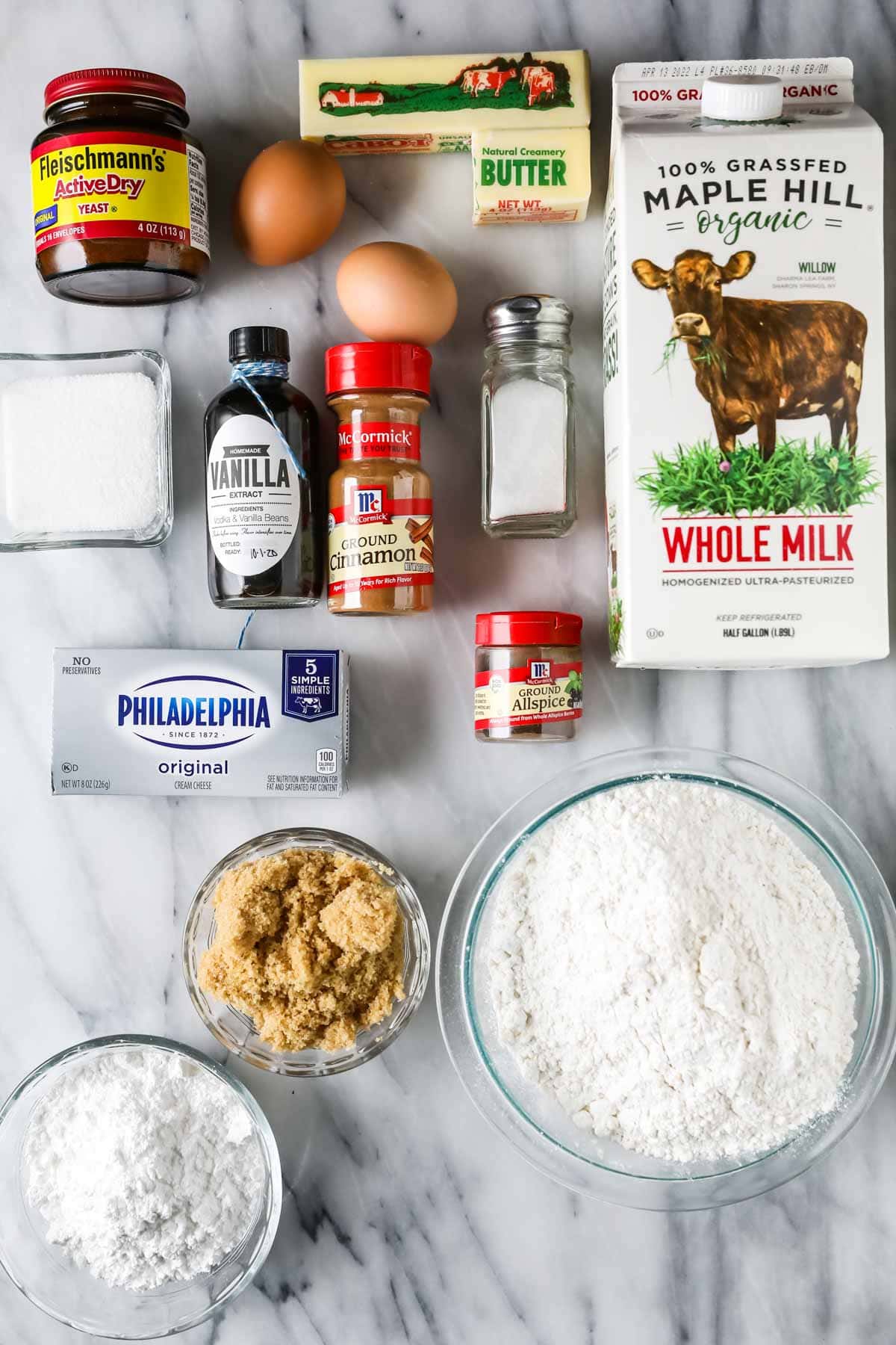 Overhead view of ingredients including yeast, butter, cinnamon, brown sugar, and more.