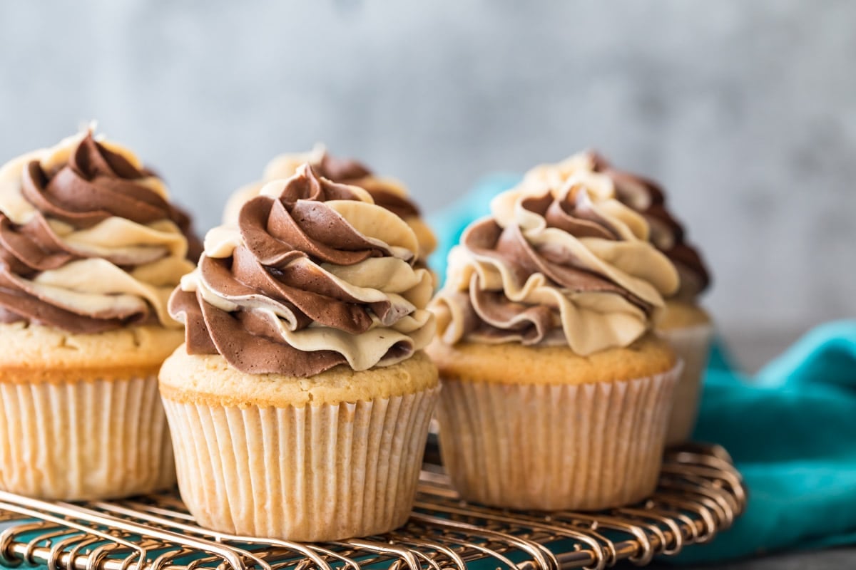 Swirled chocolate peanut butter frosted cupcakes on a cooling rack.