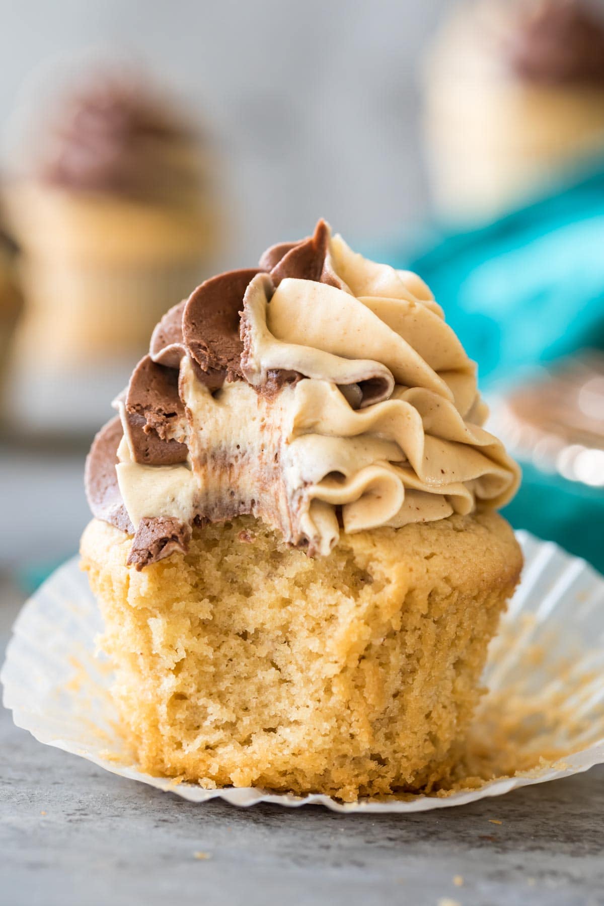 Cupcake topped with a swirled chocolate peanut butter icing that's been bitten into.