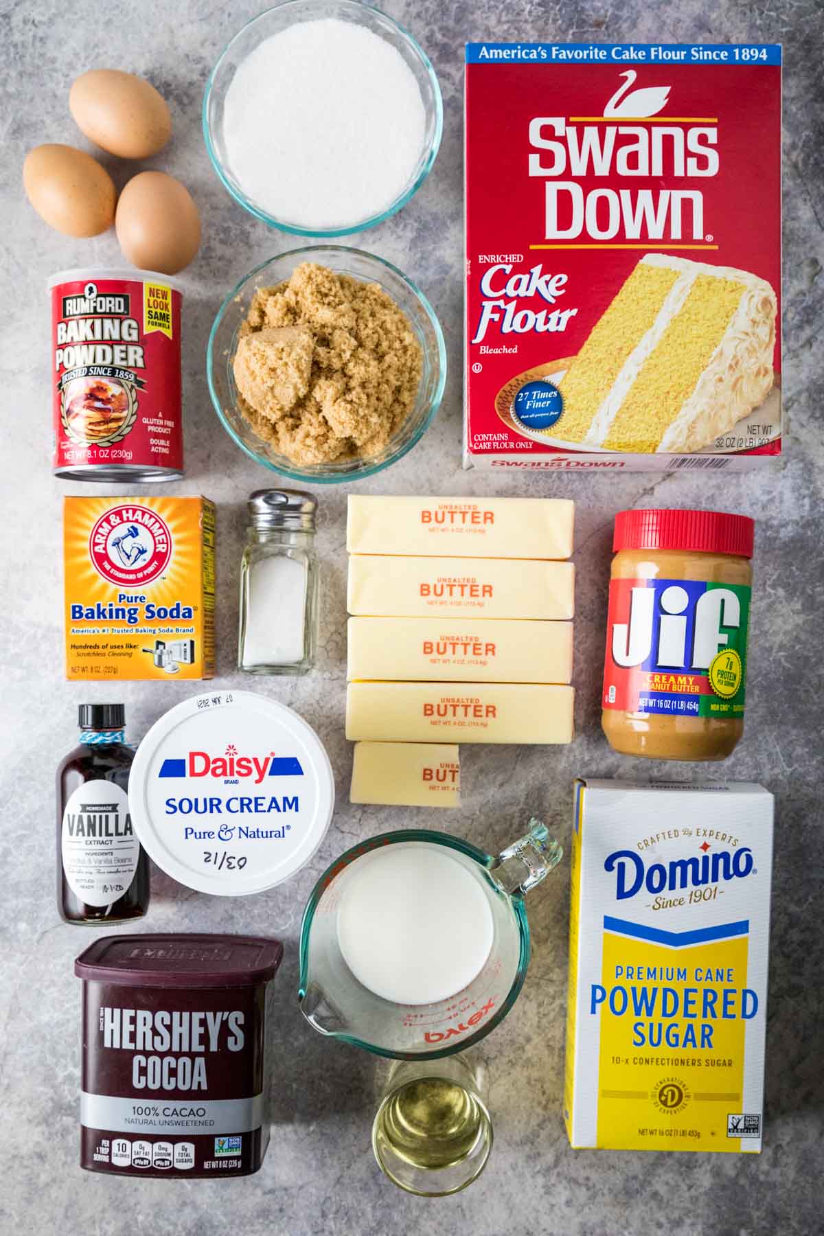 Overhead view of ingredients including cake flour, peanut butter, cocoa powder, sour cream, and more.