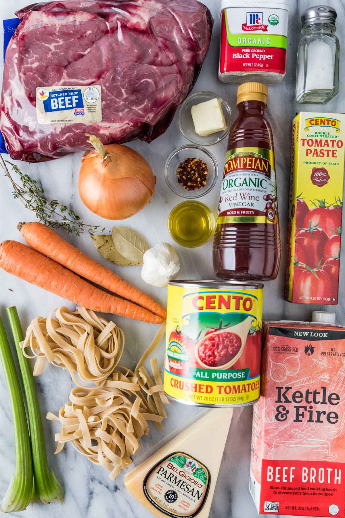 Overhead view of ingredients including beef, carrots, pasta, parmesan, and more.