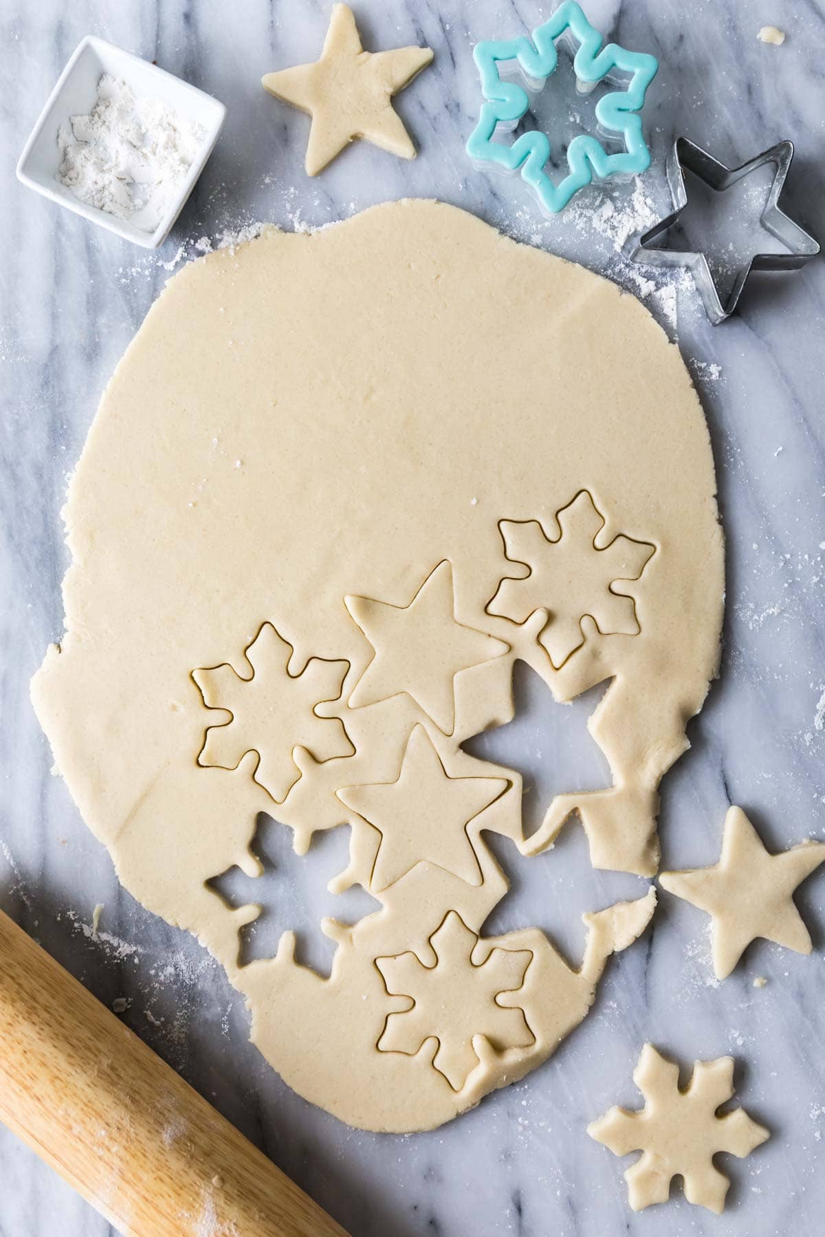 overhead of rolled out no-chill sugar cookie dough with multiple star and snowflake shaped cutouts