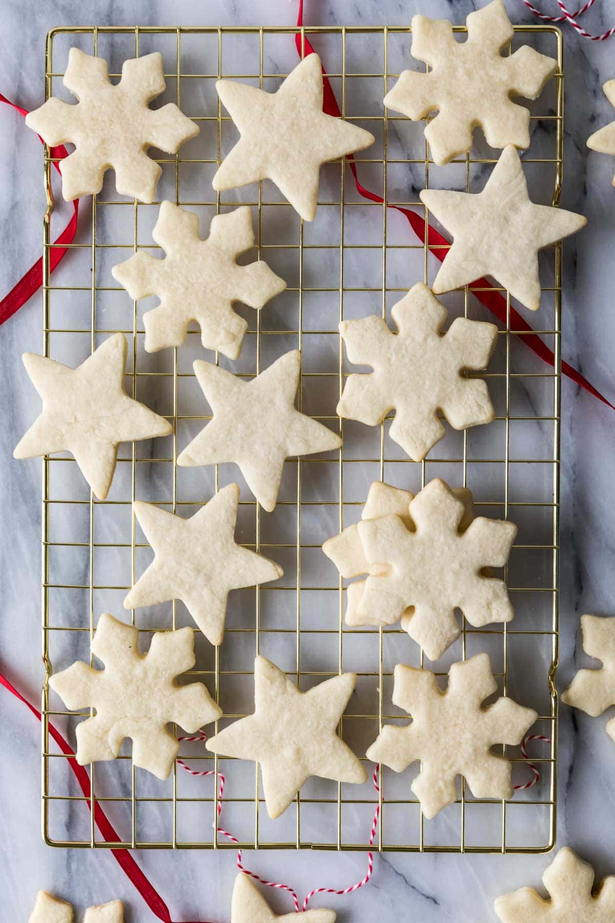 overhead of baked sugar cookies that have been cut into snowflake and star shapes