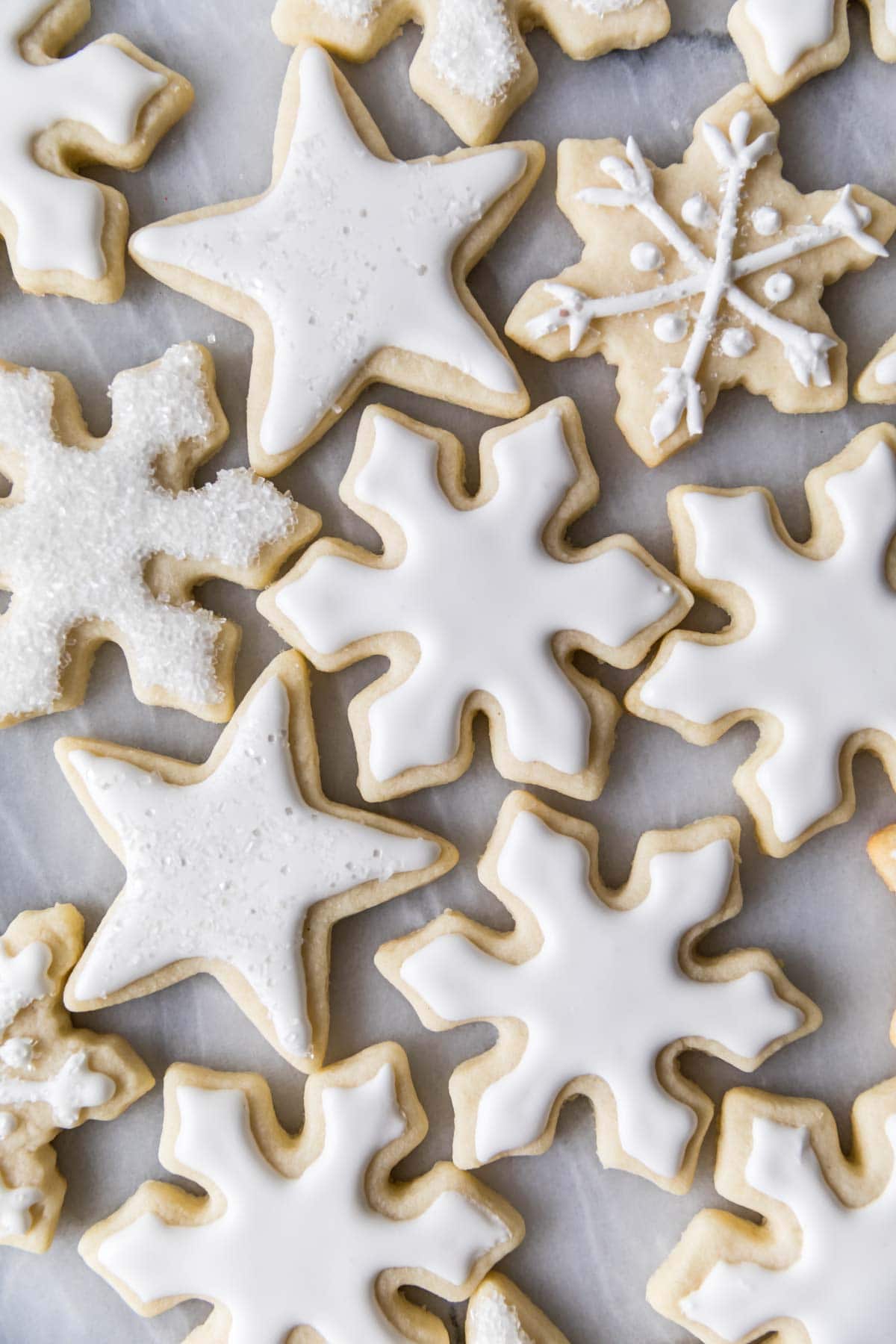 close-up of snowflake and star shaped sugar cookies frosted with white icing