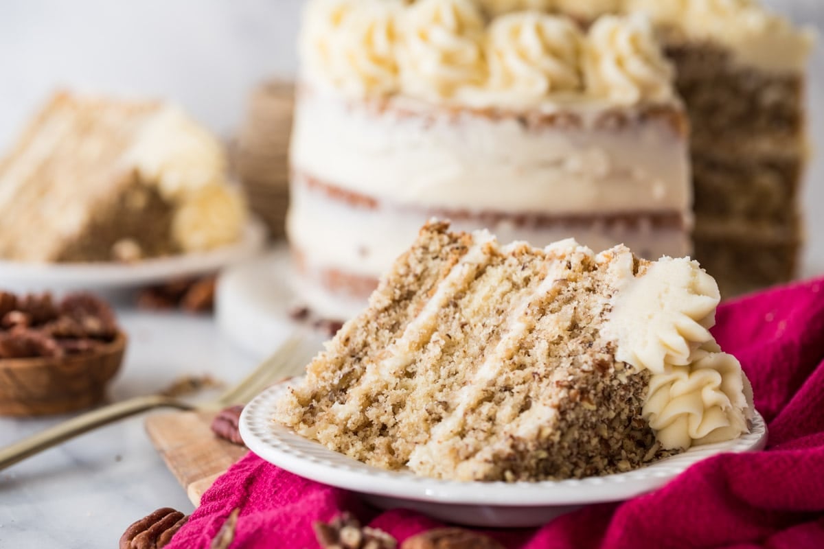 Slice of three layer butter pecan cake on a plate.