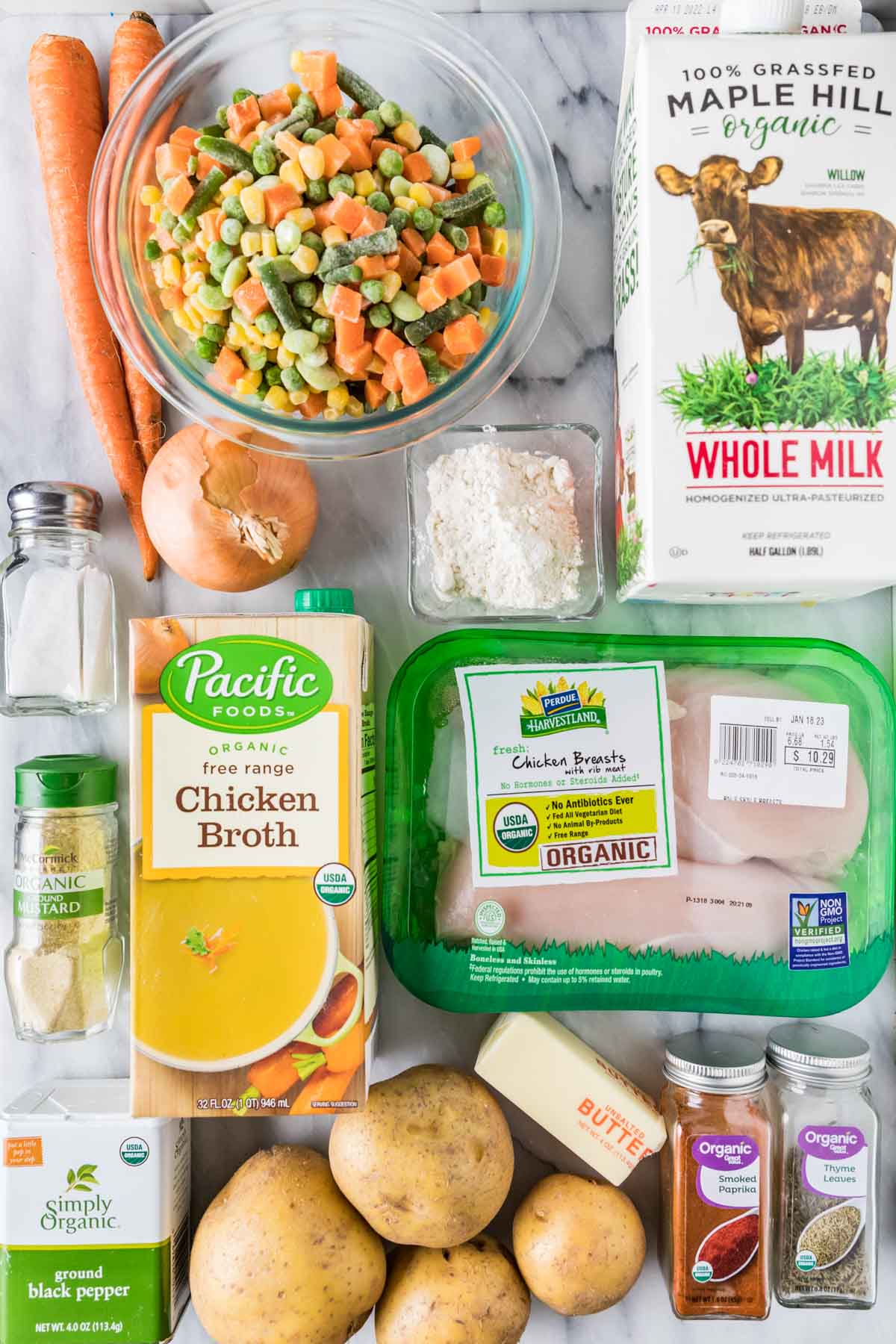 Overhead view of ingredients including frozen vegetables, carrots, potatoes, chicken, and more.