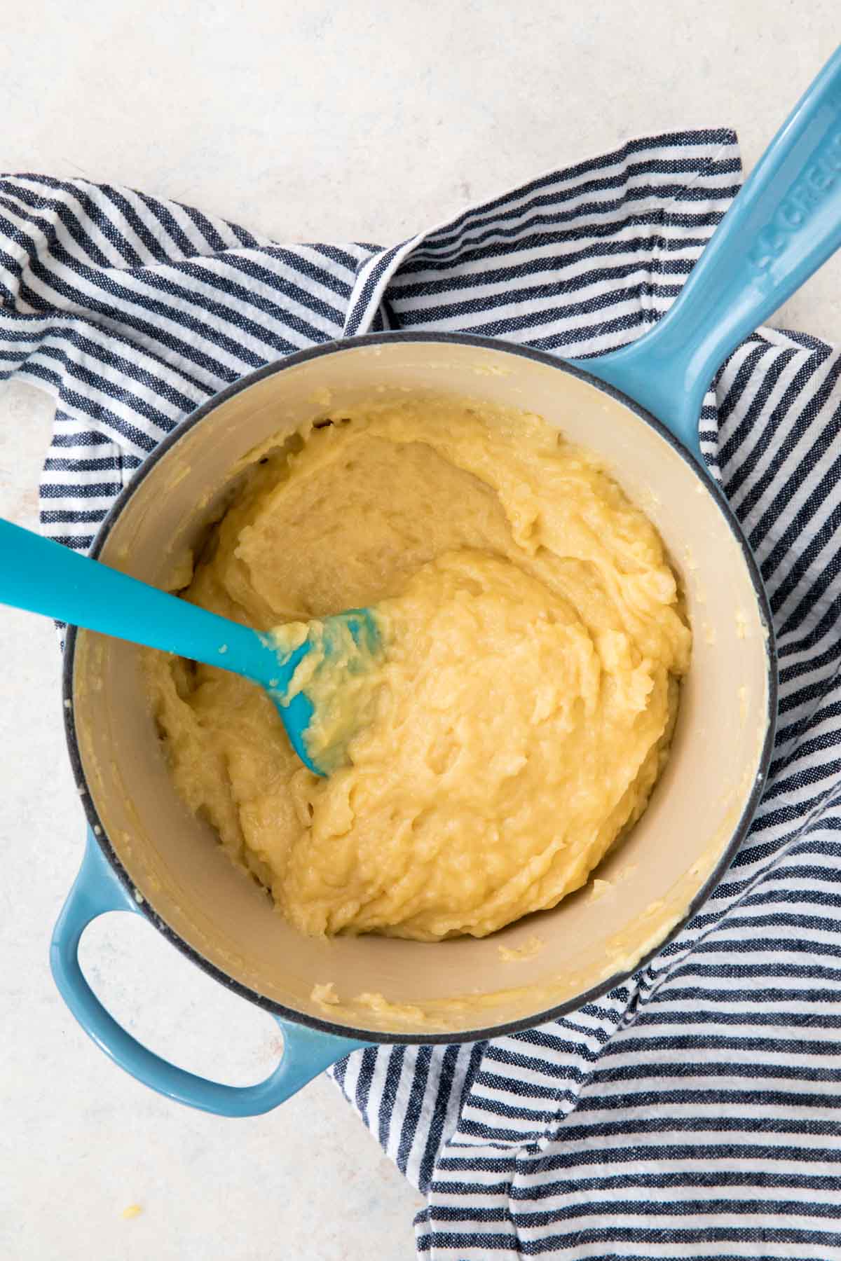 Overhead view of soft choux dough in a pot.