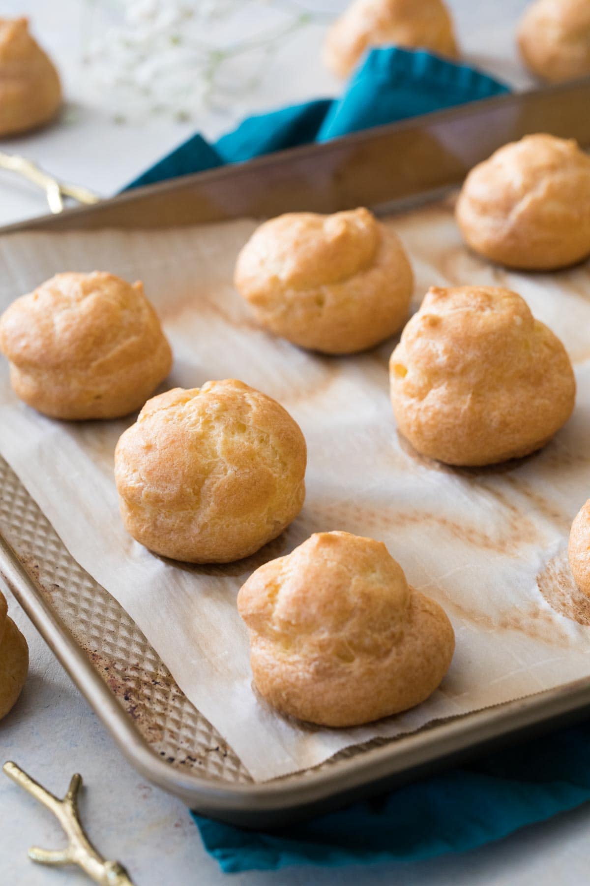 Choux buns after baking on a parchment lined baking sheet.