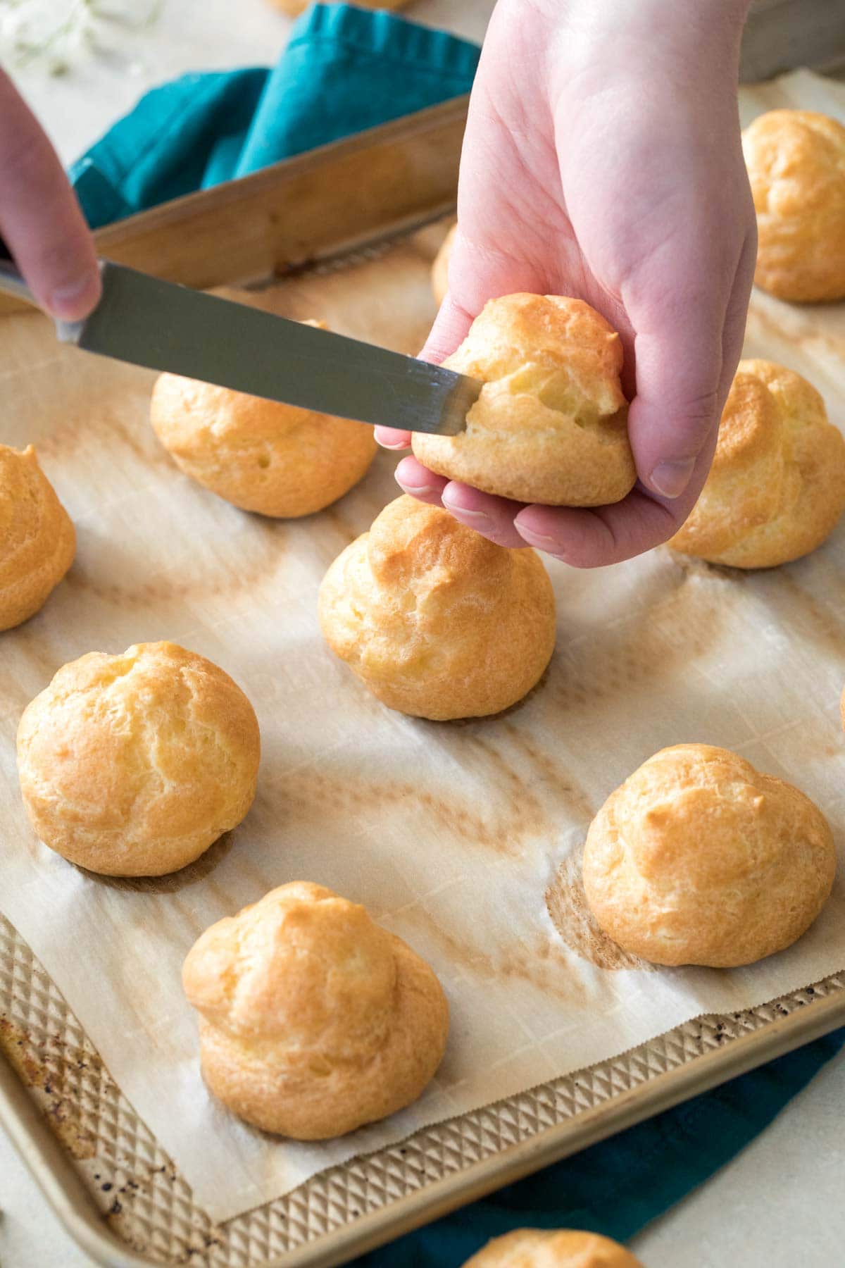 Knife cutting a hole into a choux bun.