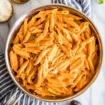 Overhead view of a skillet of penne alla vodka topped with parmesan and fresh basil.
