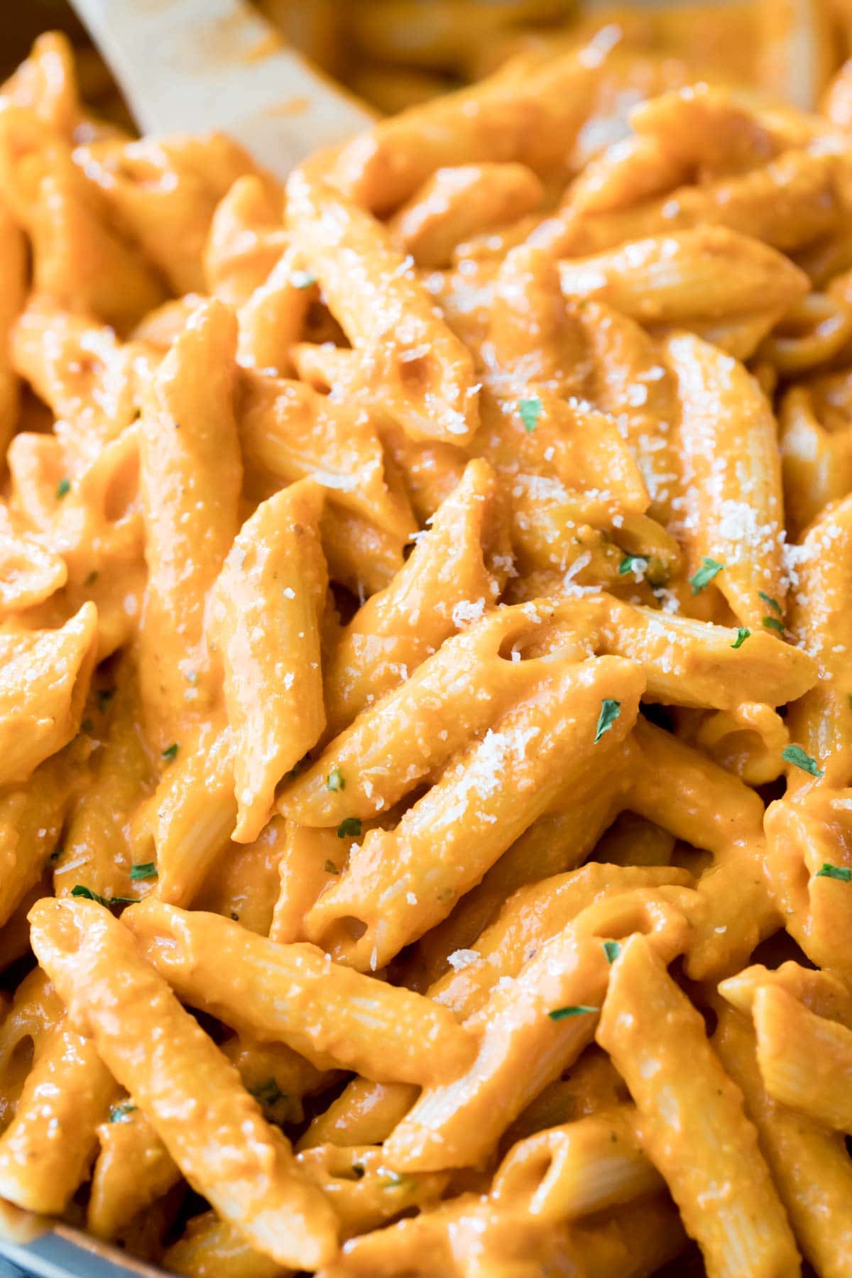 Close-up view of penne alla vodka topped with parmesan and fresh basil.