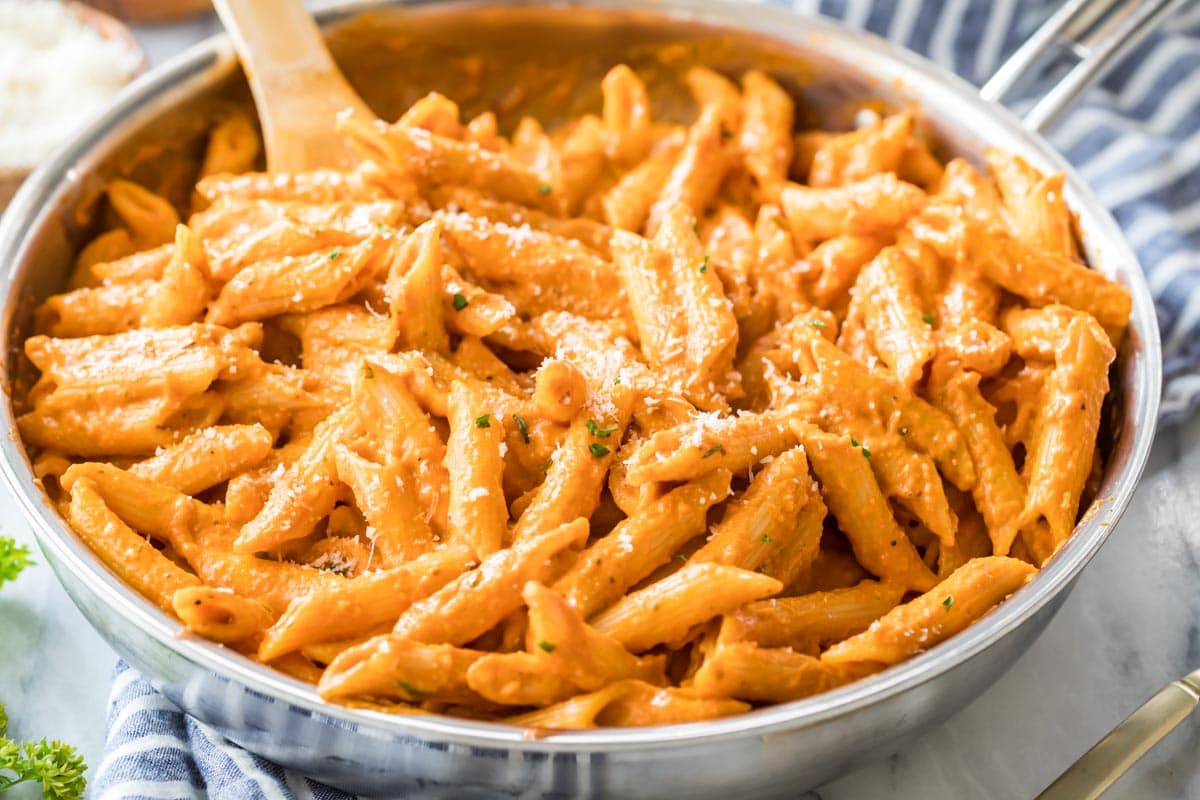 Skillet of penne pasta in a tomato vodka sauce topped with parmesan cheese.