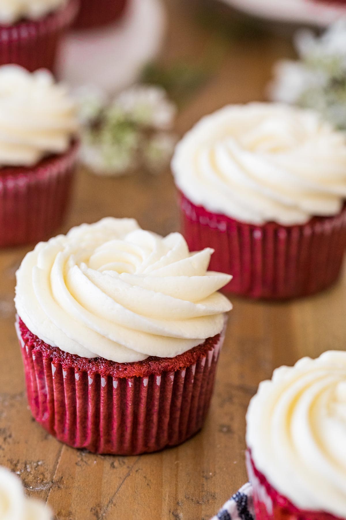 Red cupcakes topped with small swirls of ermine frosting.