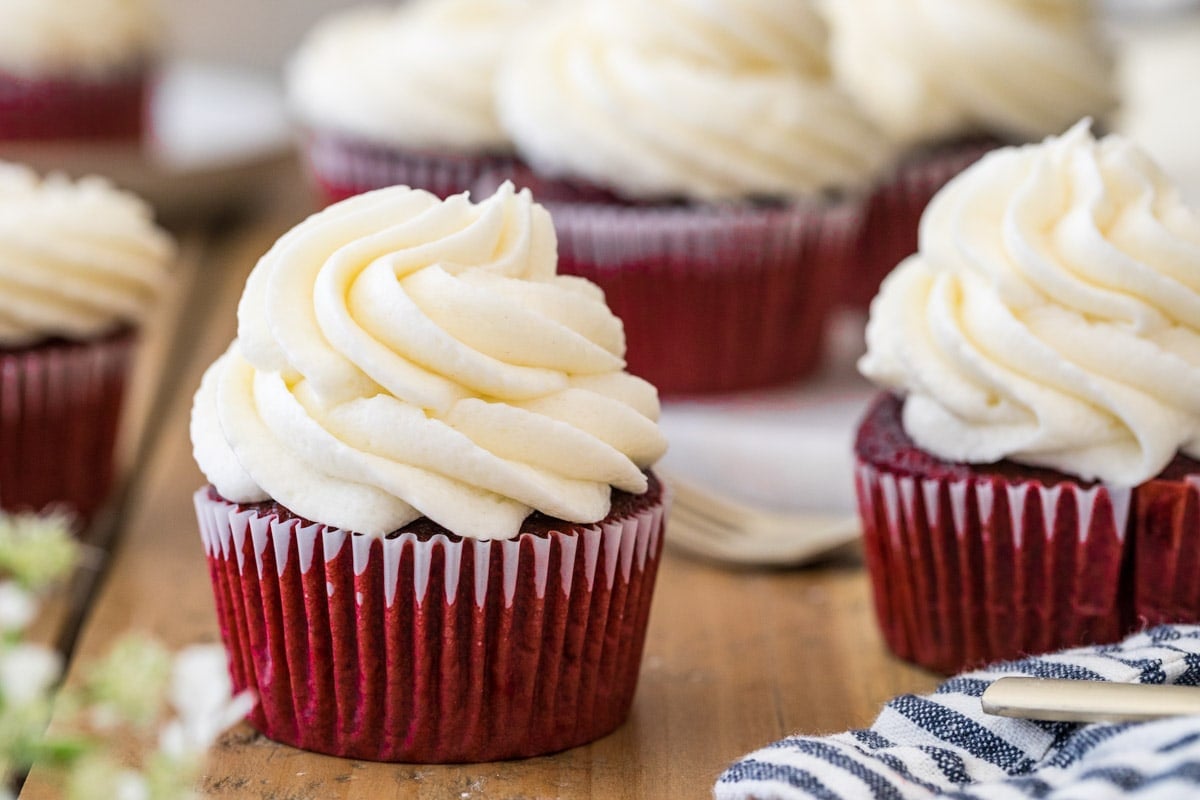 Red cupcakes topped with large piped swirls of ermine frosting.