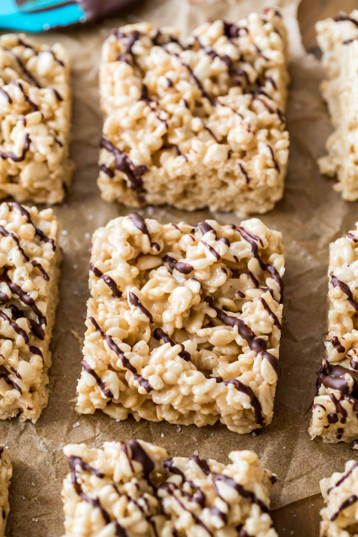 Rows of rice krispie treats topped with a chocolate drizzle.