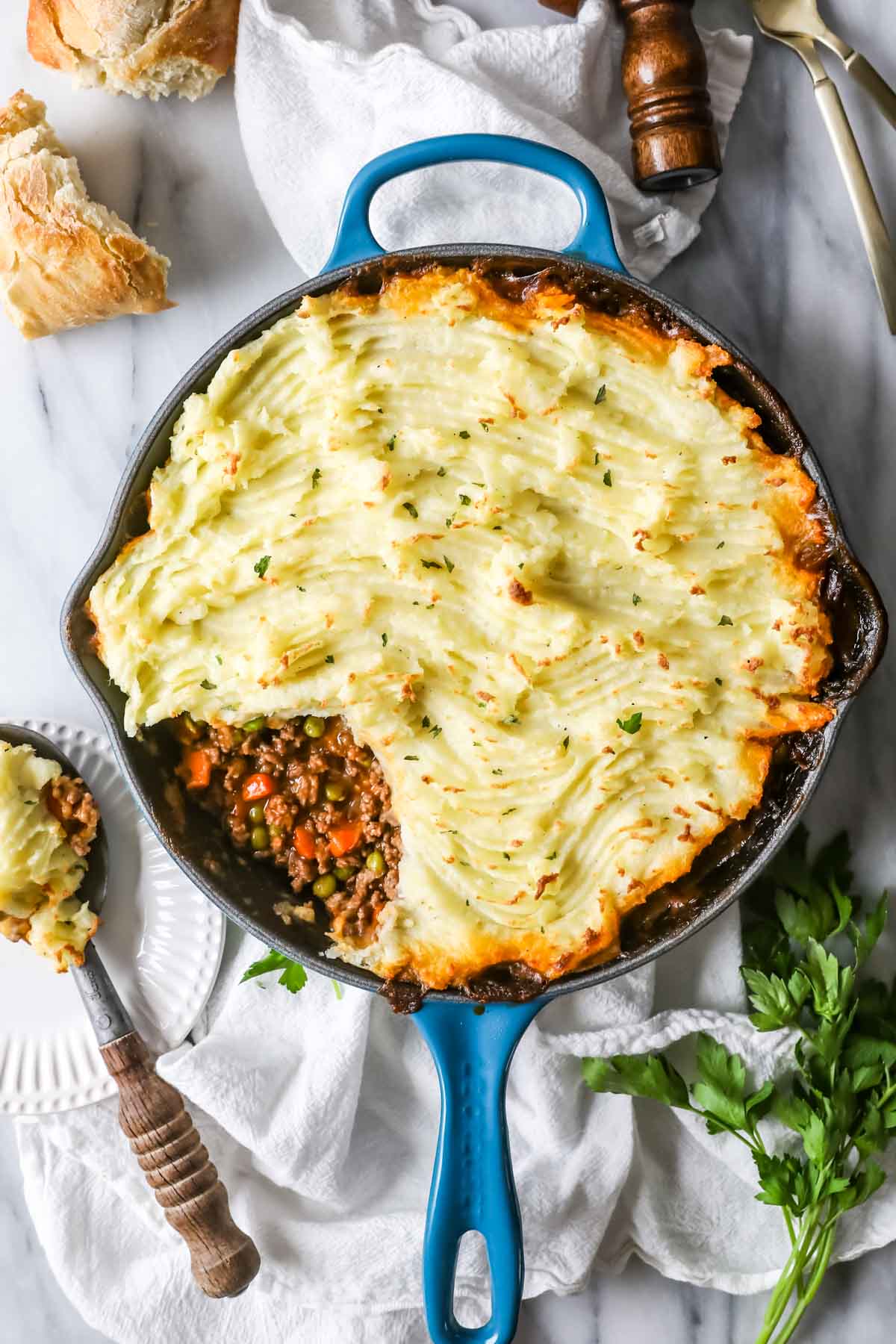 Overhead view of a skillet of shepherd's pie with one spoonful missing to show the vegetable and meat filling.