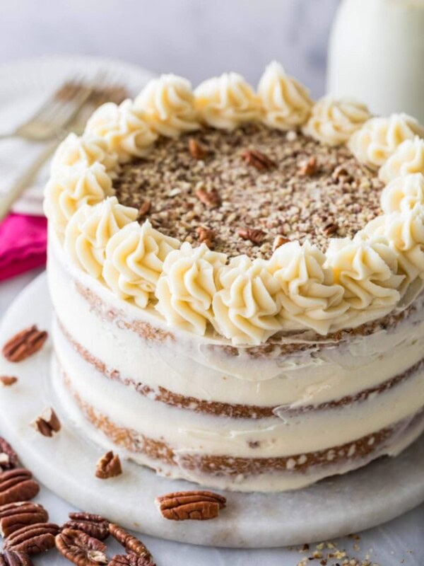 Cake frosted naked style with finely chopped pecans and icing swirls on top.