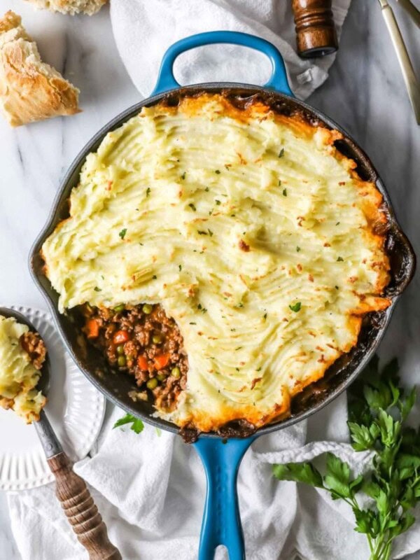 Overhead view of a skillet of shepherd's pie with one spoonful missing to show the vegetable and meat filling.