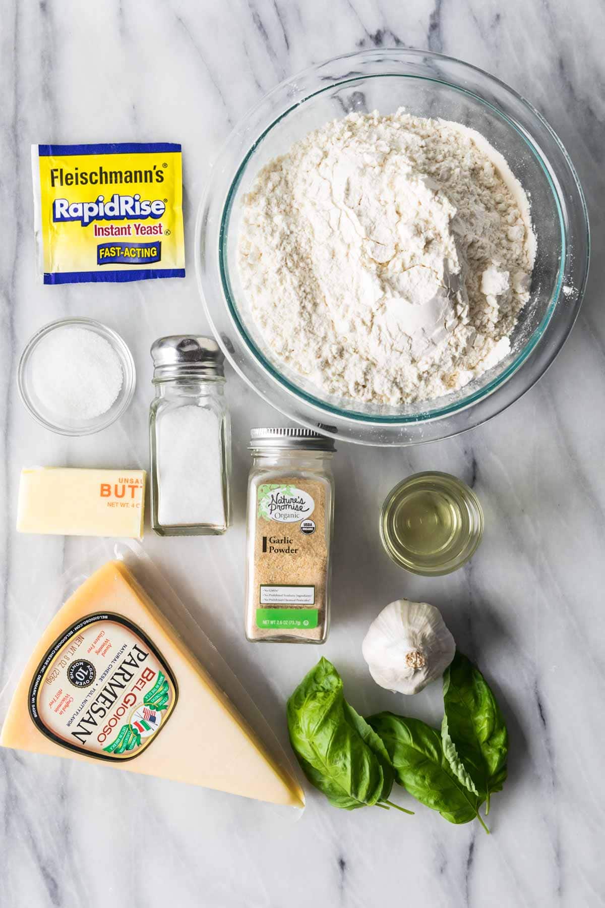 Overhead view of ingredients including garlic, flour, parmesan, yeast, and more.