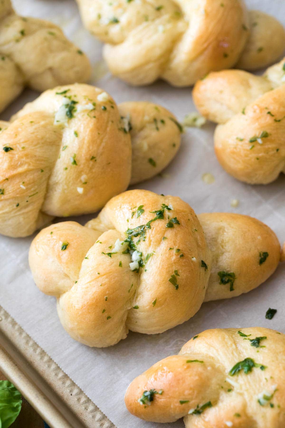 Garlic knots topped with garlic butter and fresh basil after baking.