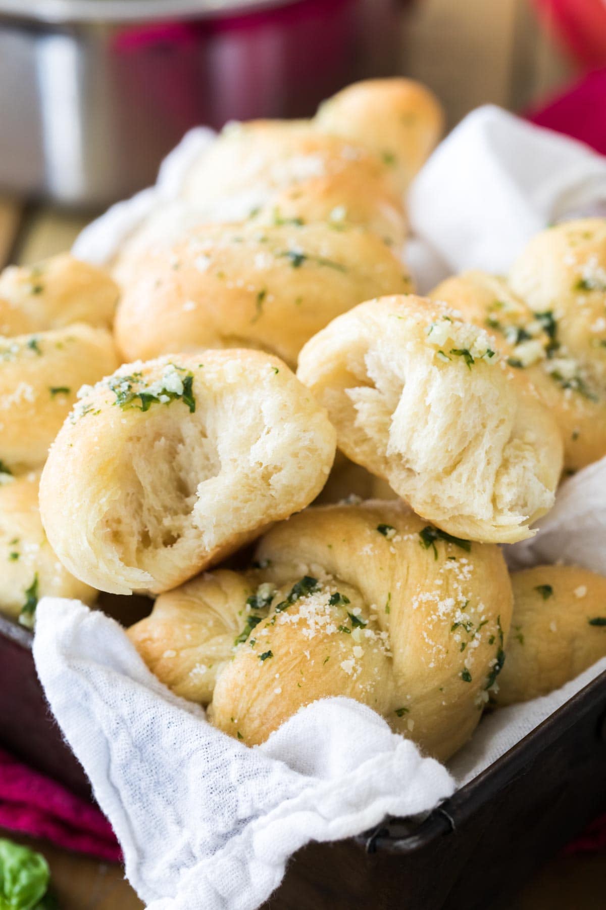 Pile of bread knots with the top knot torn in half to show a fluffy interior.