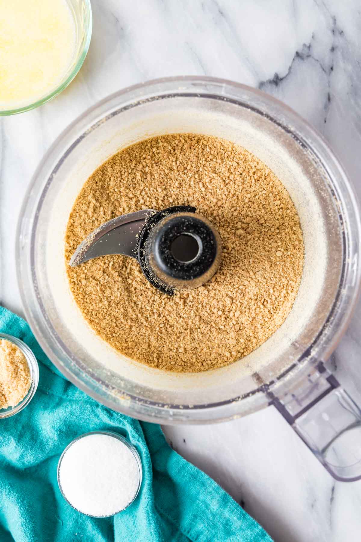 Overhead view of graham cracker crumbs in a food processor.