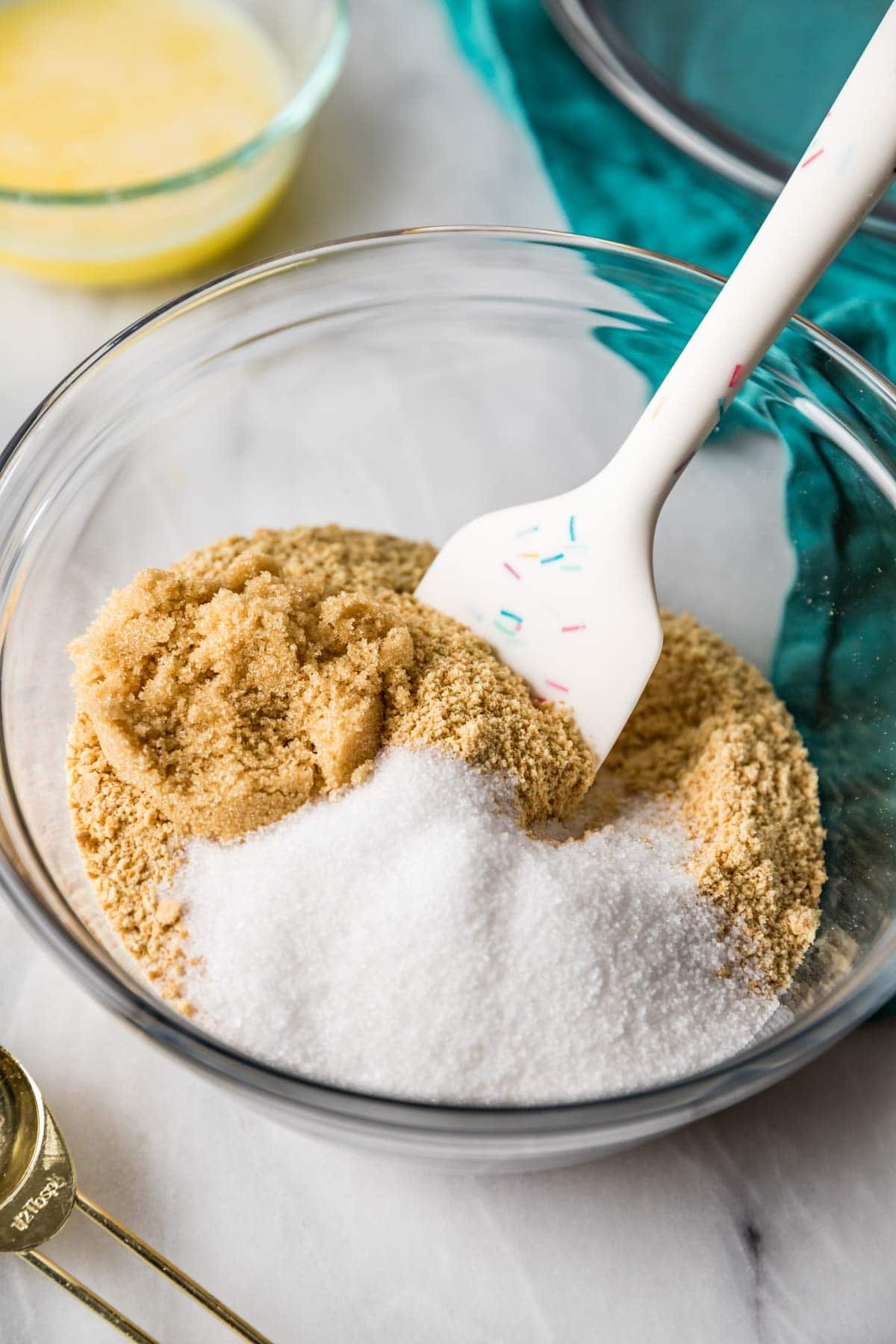Graham cracker crumbs and sugar being stirred together with a spatula.