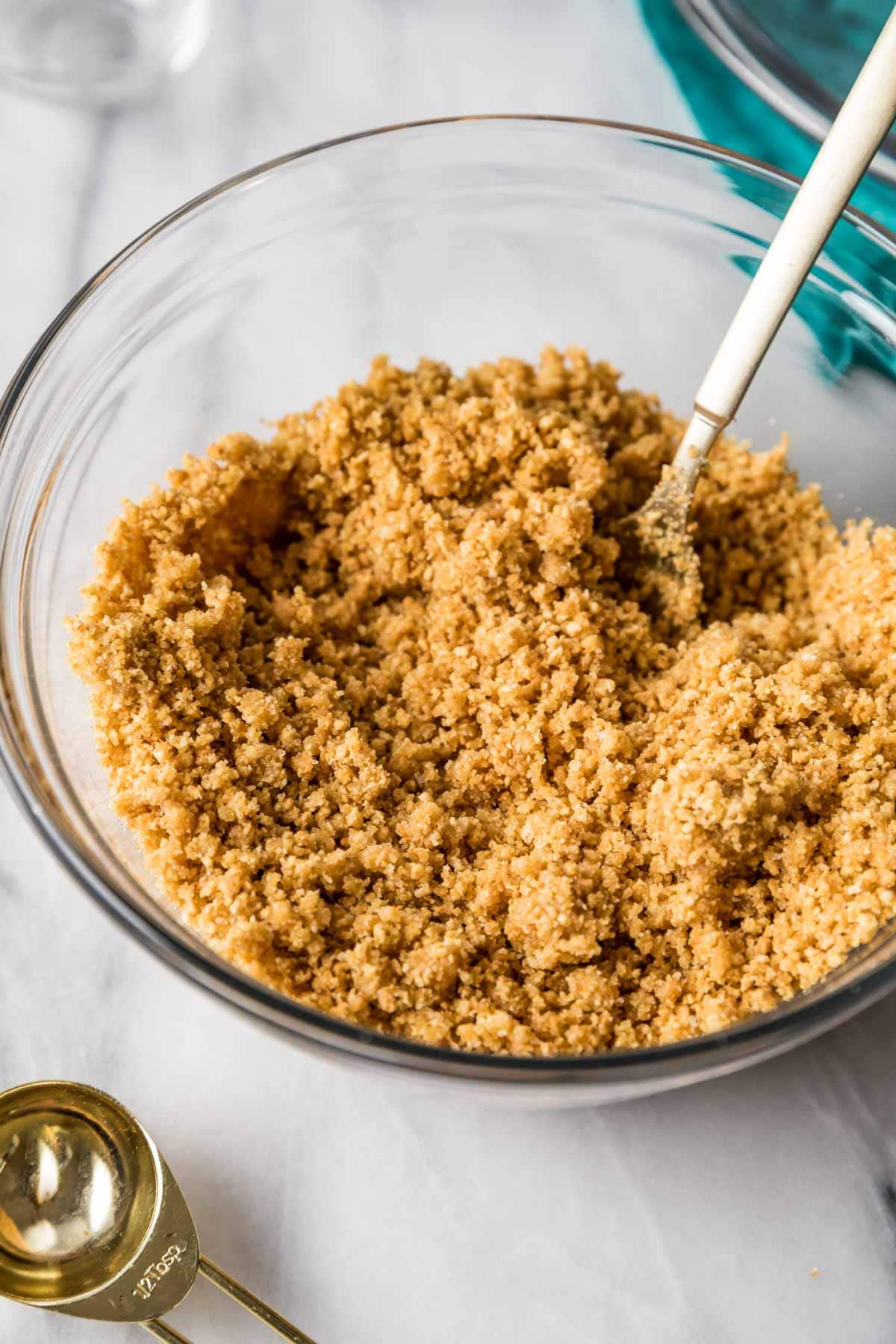 Fork tossing graham cracker crumbs together with butter and sugar.