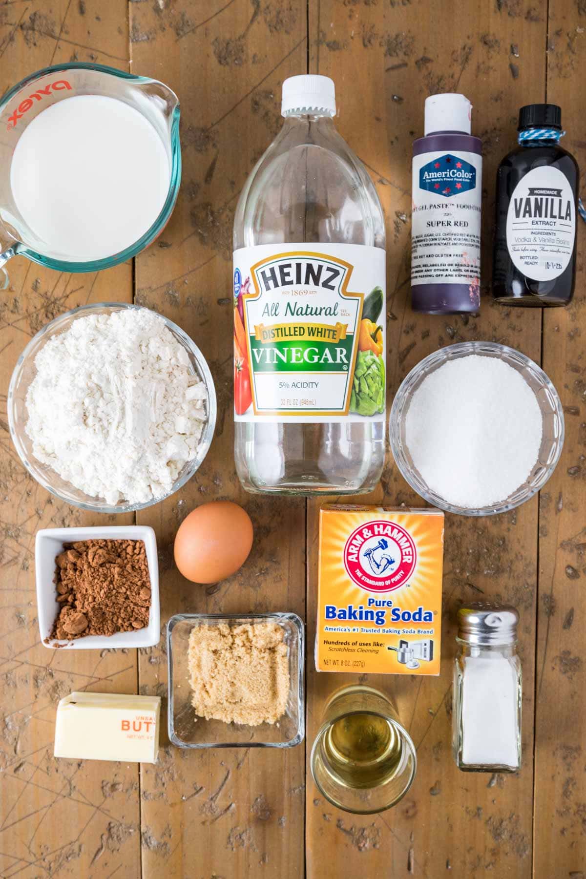 Overhead view of ingredients including vinegar, red food coloring, cocoa powder, and more.