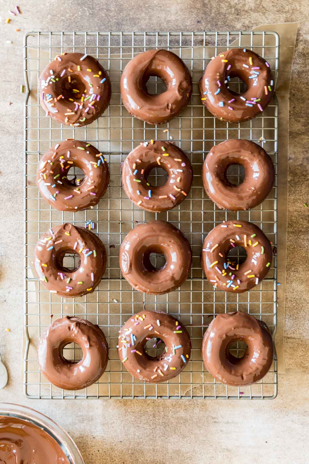 Overhead view of chocolate donuts in rows on a cooling rack.