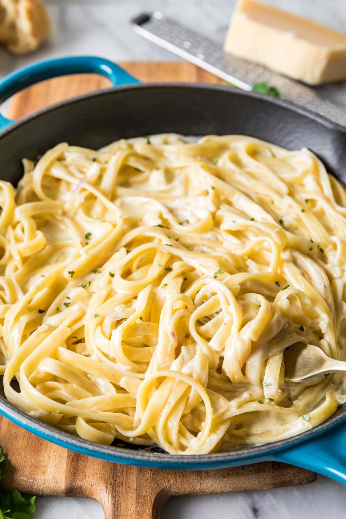 Fork twirling fettuccine pasta coated in a silky alfredo sauce.