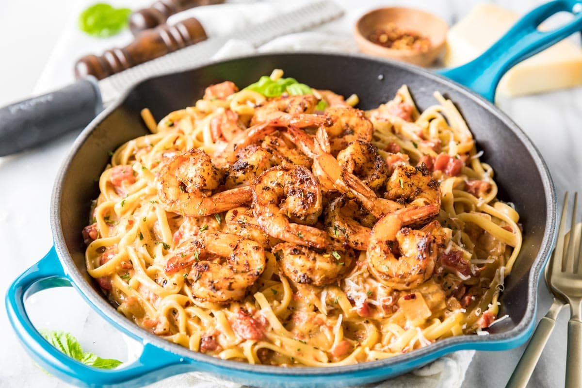 Skillet of linguine pasta topped with seasoned shrimp.