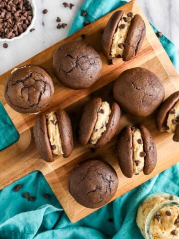 Overhead view of cookie dough whoopie pies on a wood cutting board.