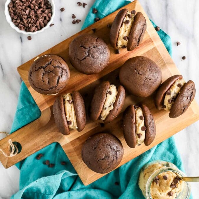Overhead view of cookie dough whoopie pies on a wood cutting board.