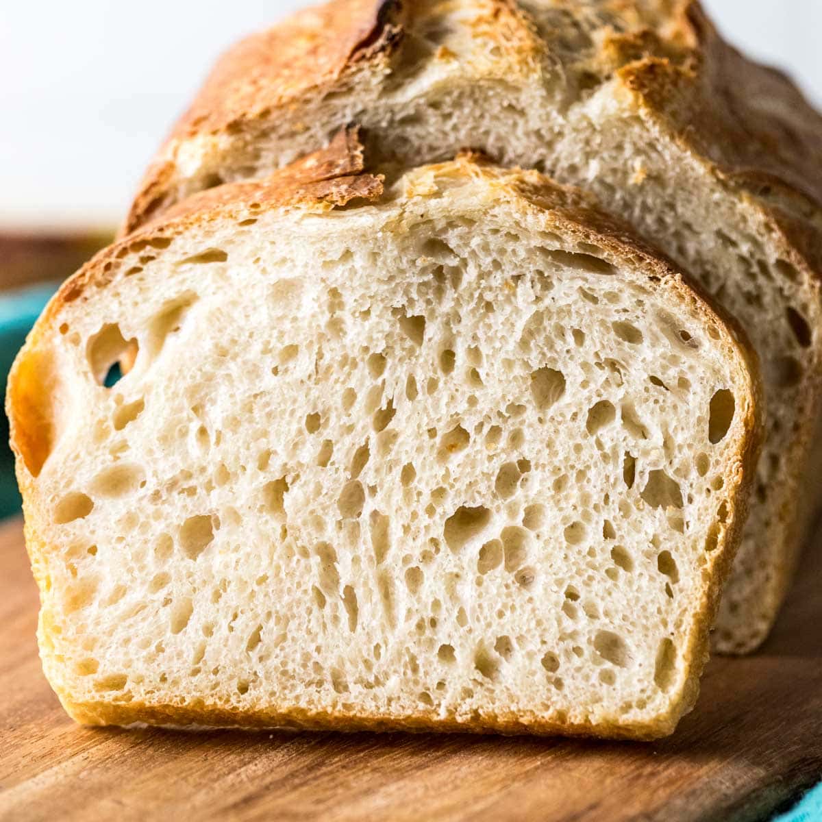 Sourdough bread slice in front of a homemade sourdough bread loaf.